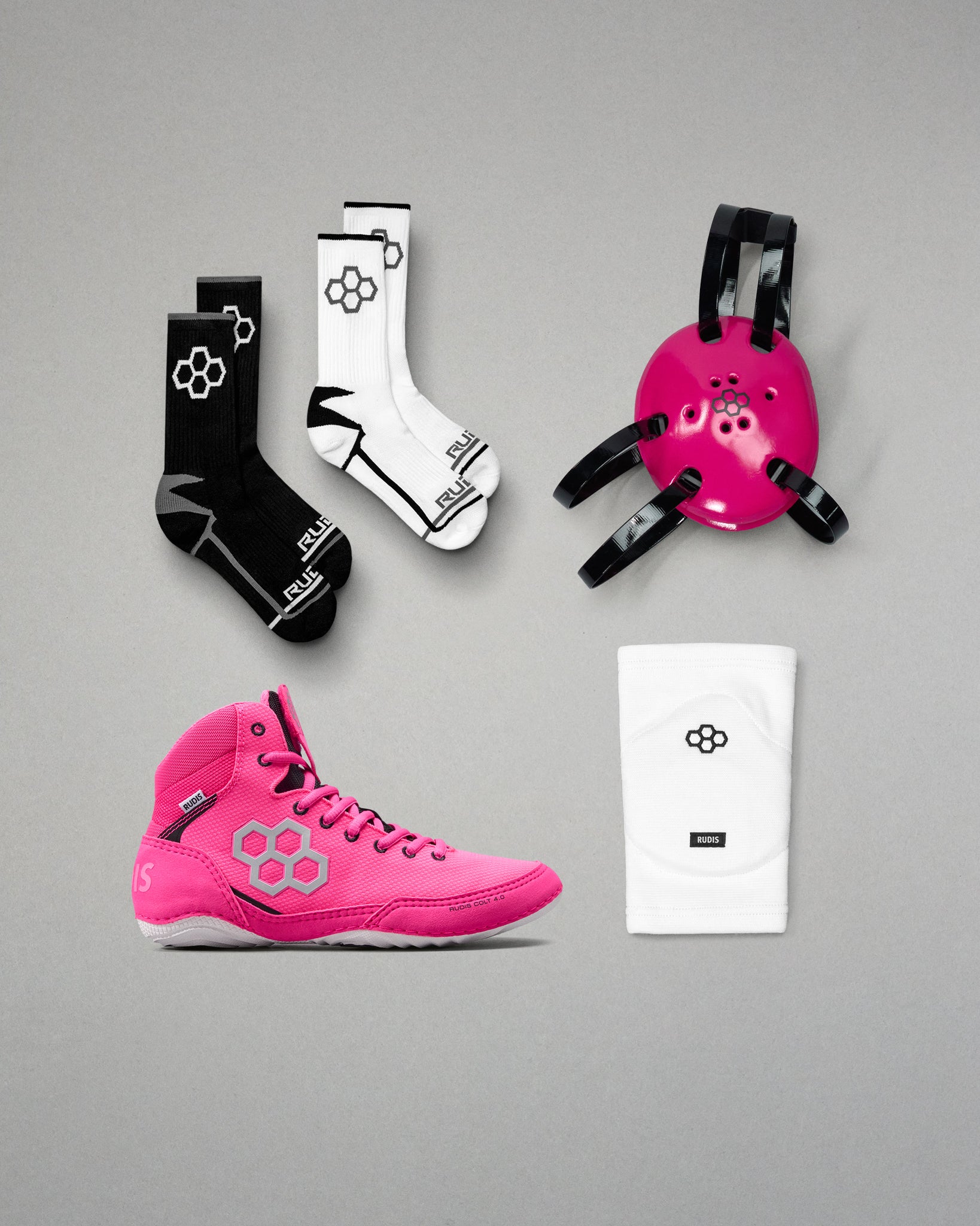 Pink wrestling shoes, socks, and headgear with a brand logo on a gray background