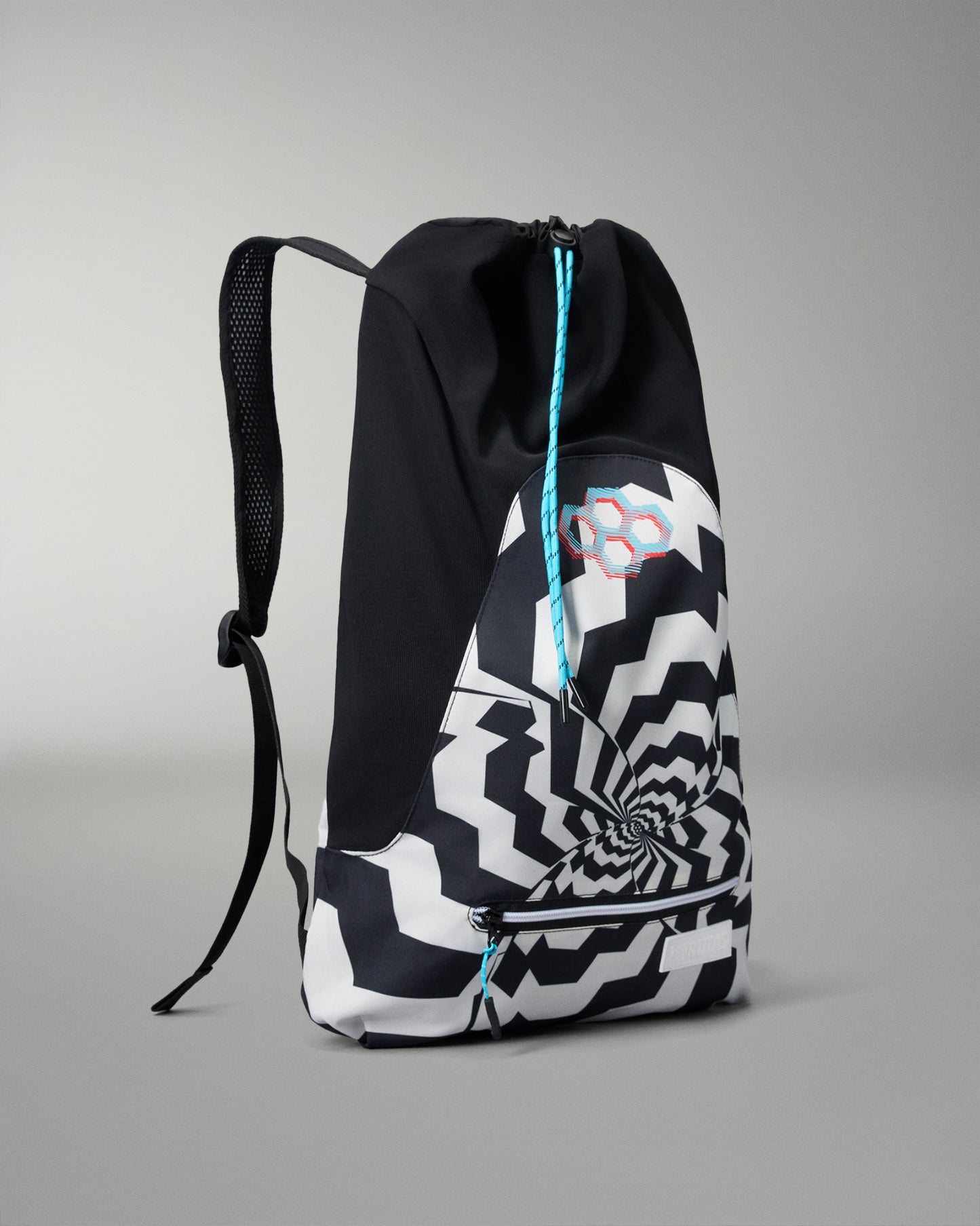 A black and white patterned drawstring backpack with a spiral optical illusion design on the front pocket, featuring a turquoise drawstring and a small geometric logo.