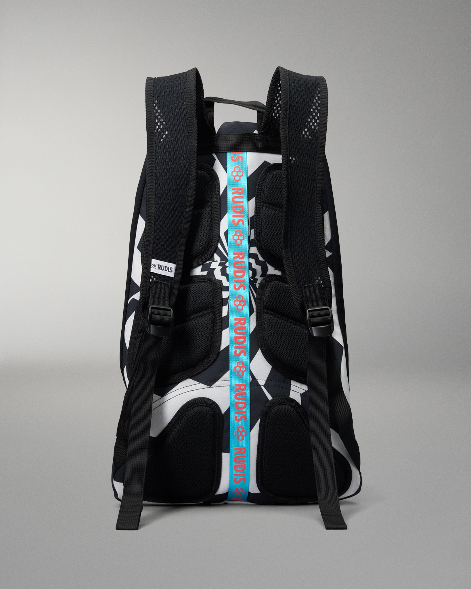 A black and white patterned backpack shown from the back, featuring a prominent vertical blue strap with white text reading 'RUDIS' and black mesh padding on the straps.