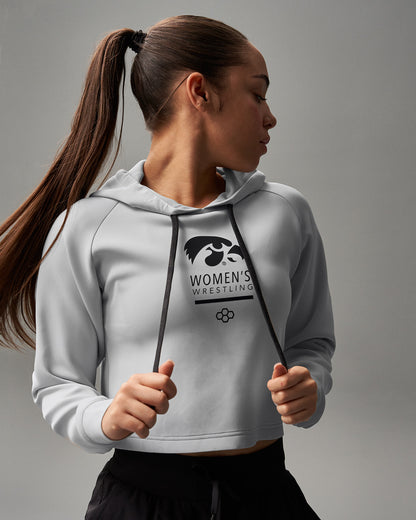 Woman wearing a gray hoodie with a logo on a gray background