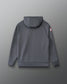 A dark gray hooded sweatshirt shown from the back, featuring a small red and white graphic on the left sleeve, photographed against a neutral gray background.