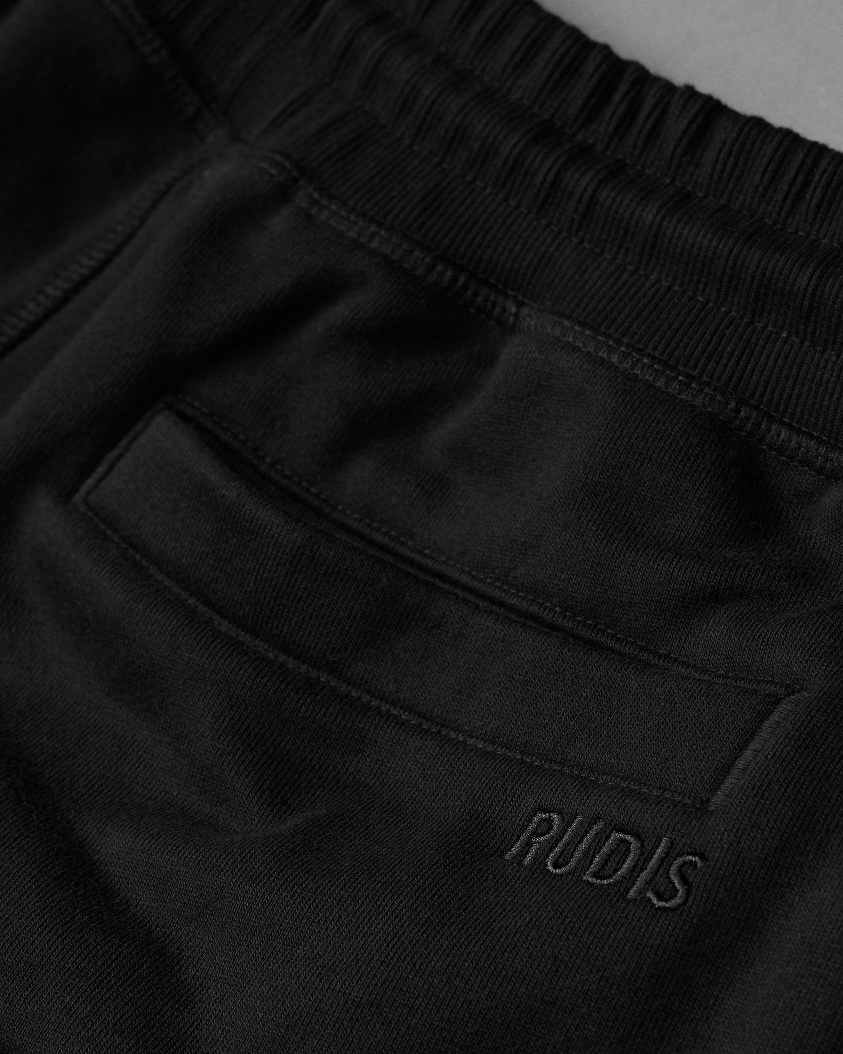 Black pants with 'RUDIS' branding on a dark background