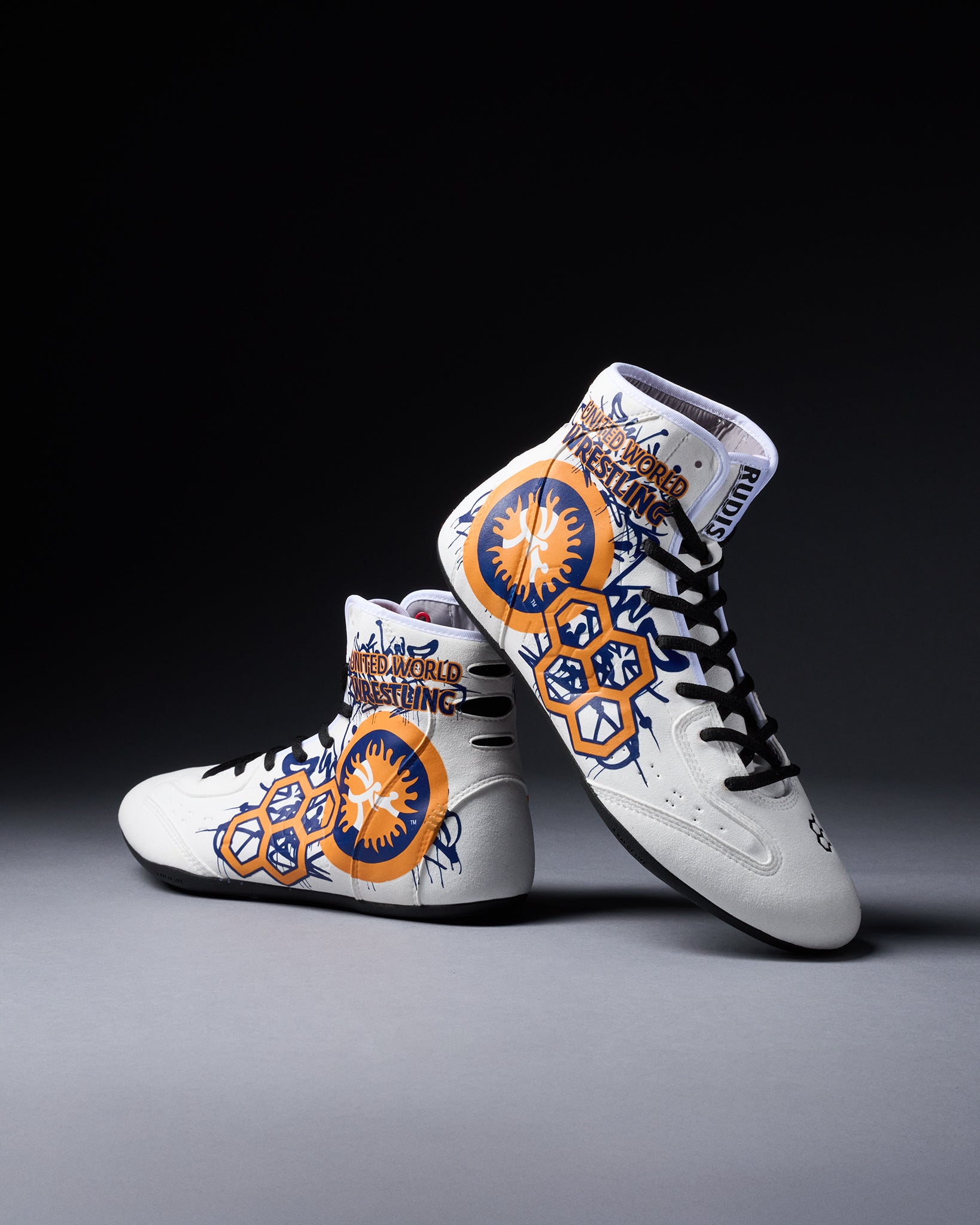 White wrestling shoes with orange and blue designs on a gray background
