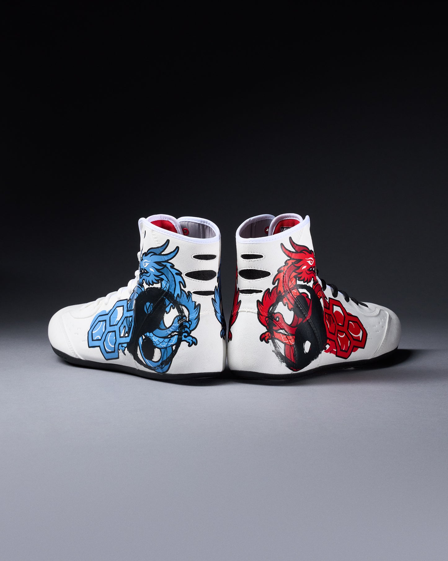White wrestling shoes with dragon designs on a gray background