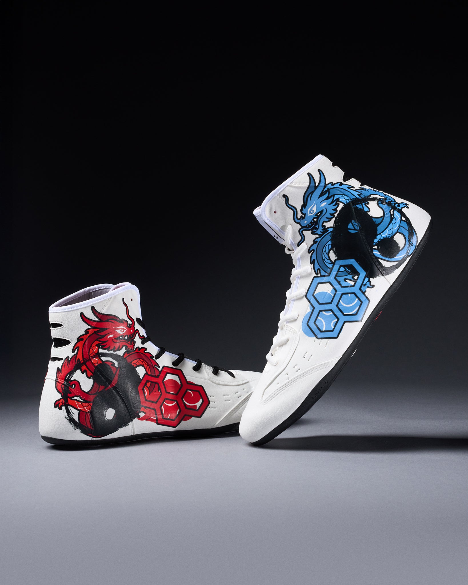 White wrestling shoes with red and blue dragon designs on a dark background