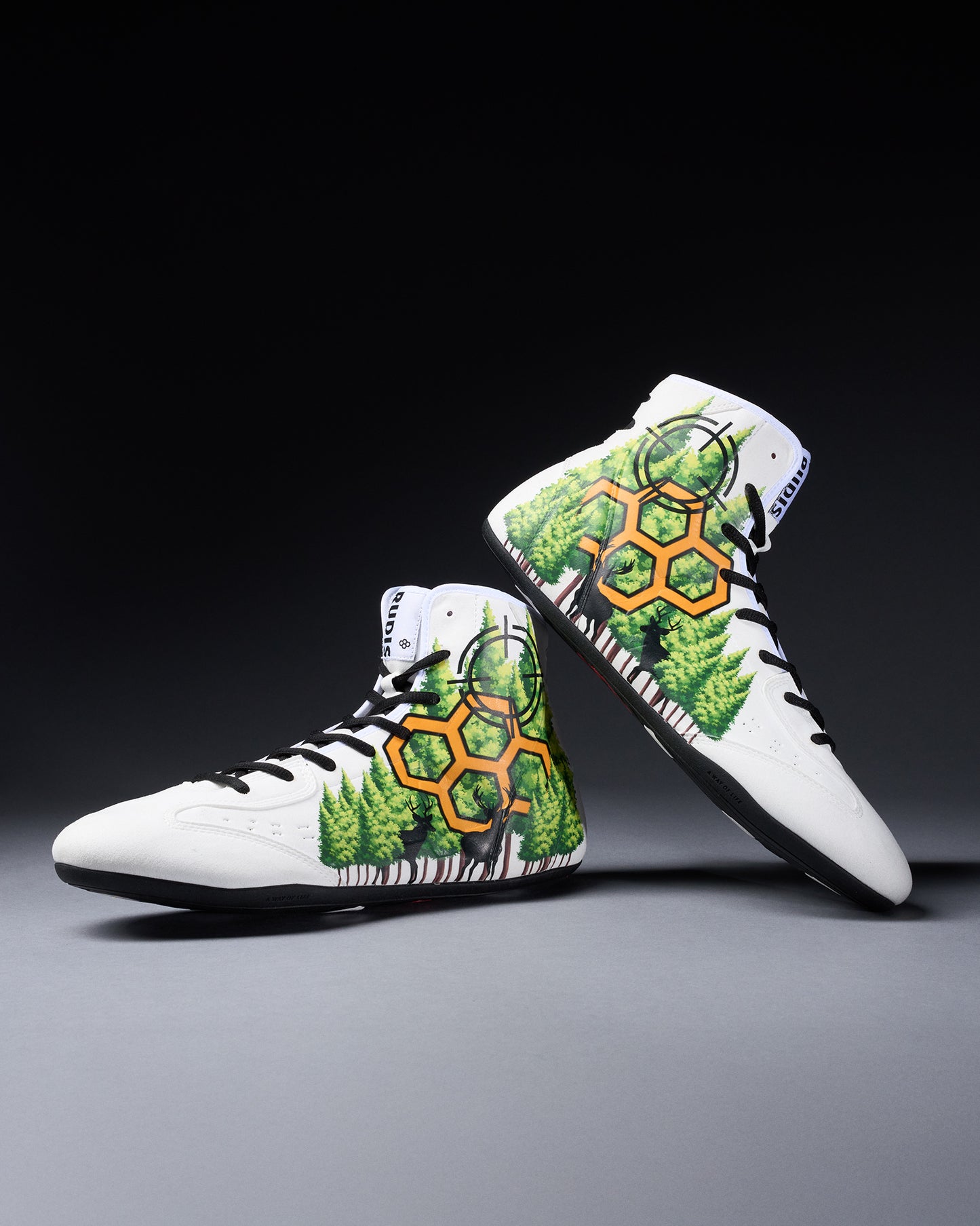 White wrestling shoes with green and orange pattern on a gray background