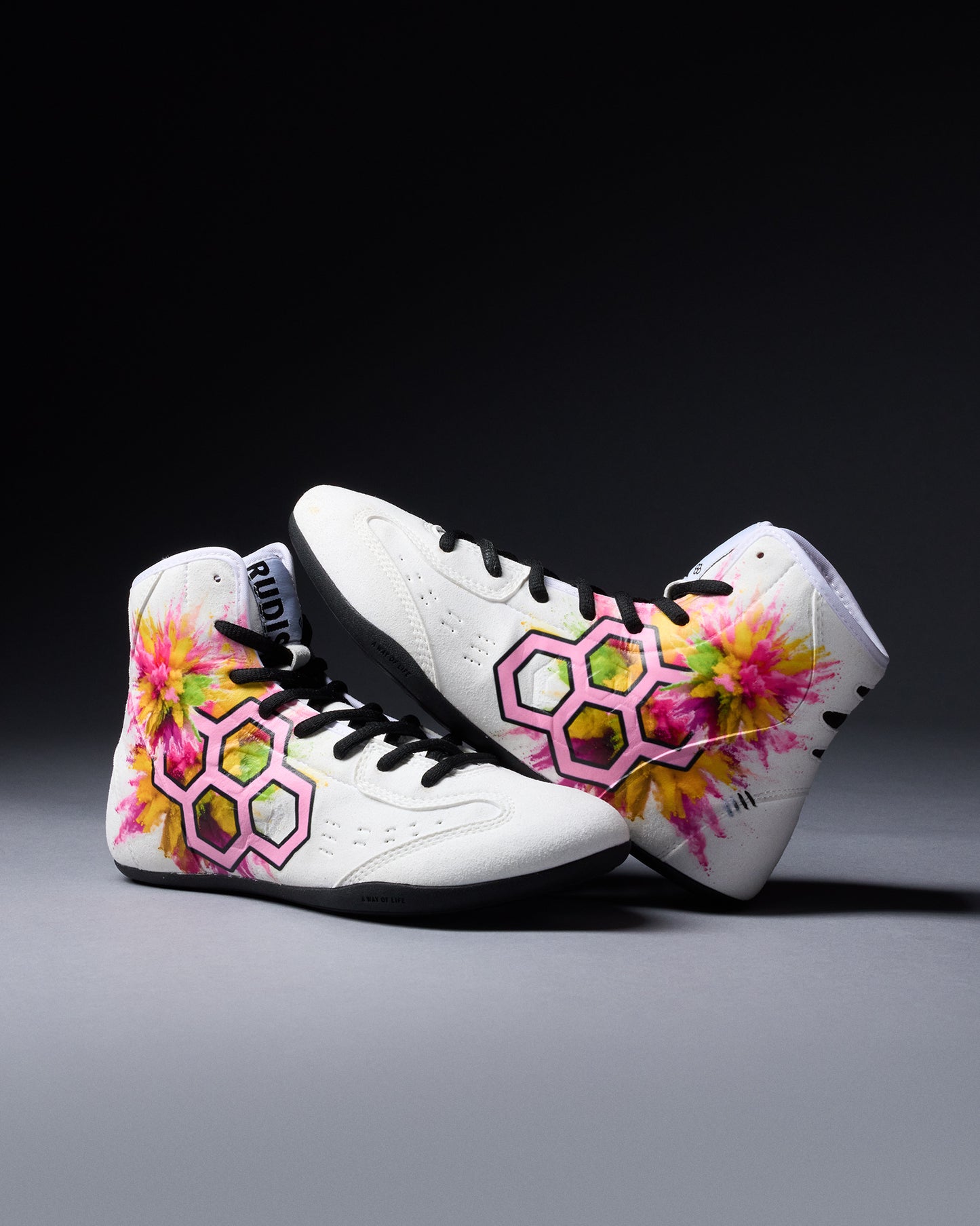White wrestling shoes with colorful floral and geometric designs on a dark background
