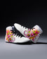 White wrestling shoes with colorful floral and geometric designs on a dark background