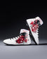 White wrestling shoes with red and black floral patterns on a gray background