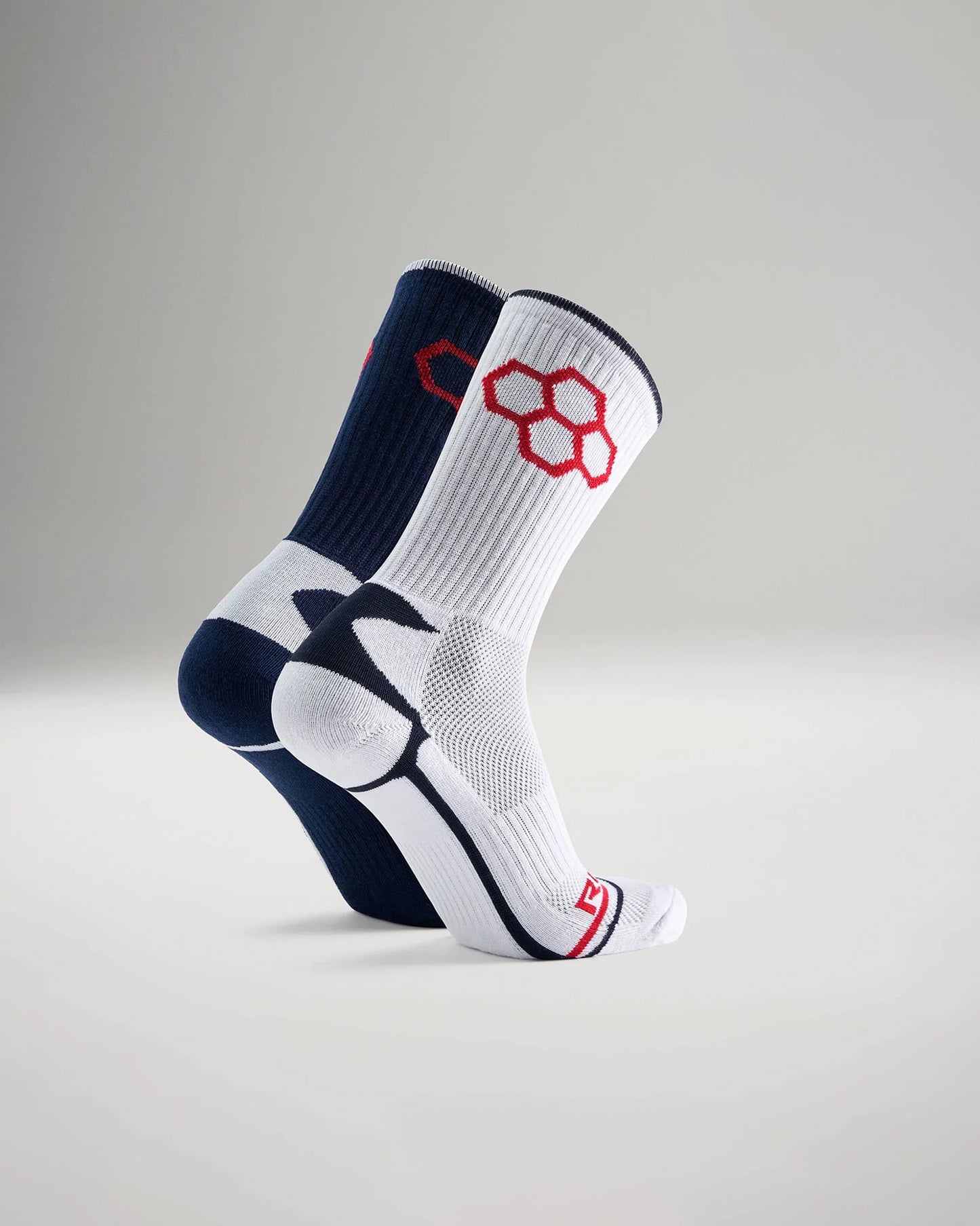 A pair of athletic socks features a contrasting navy blue and white design with red accents highlighting breathable materials for optimal performance