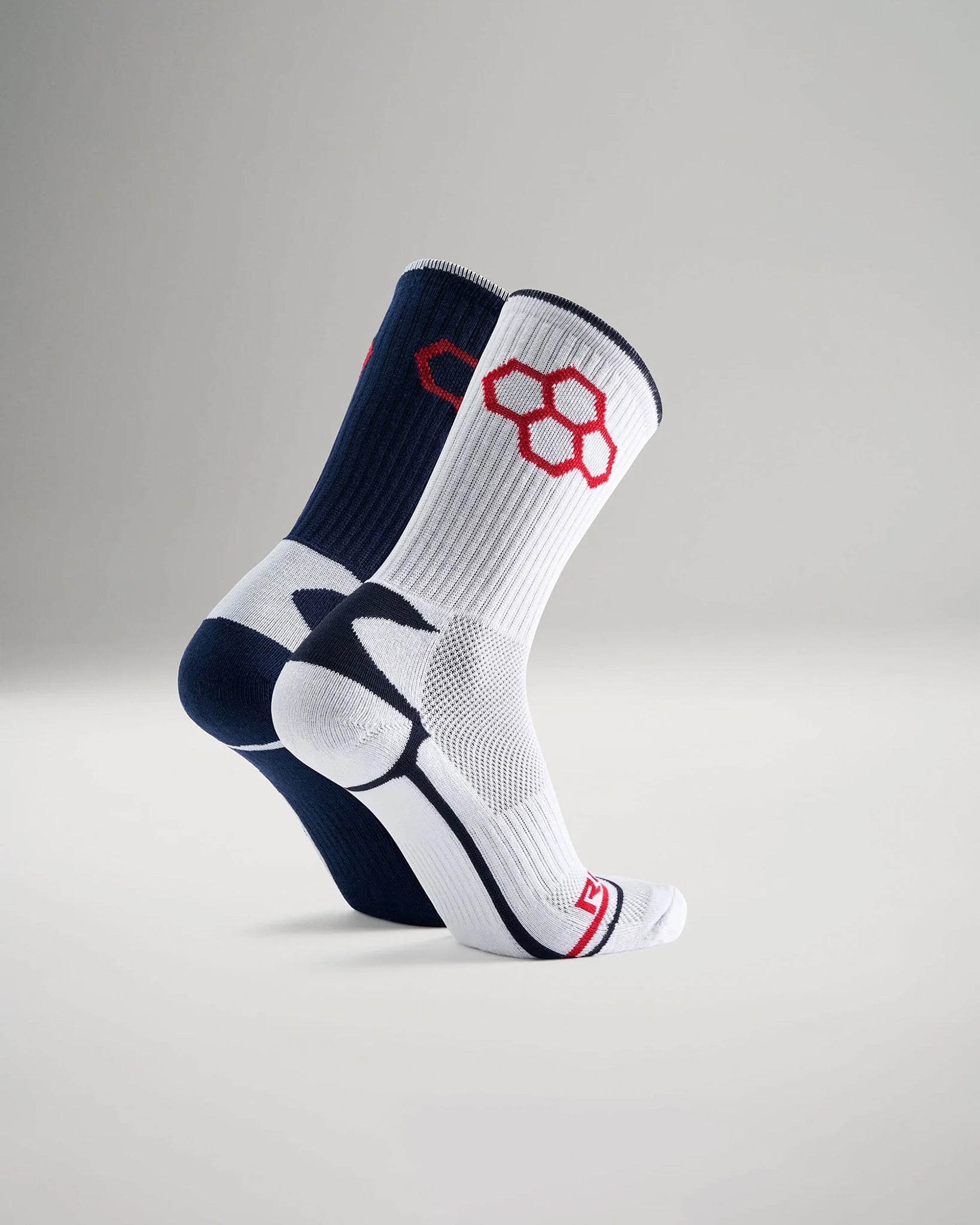 A pair of athletic socks features a contrasting navy blue and white design with red accents highlighting breathable materials for optimal performance