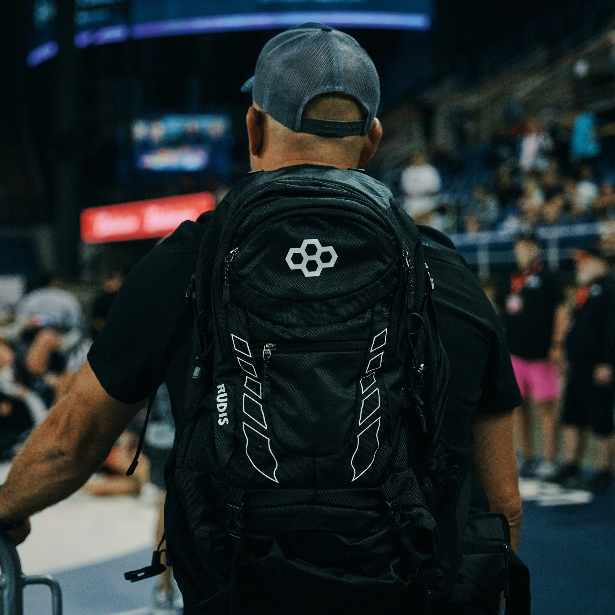 Person wearing a black backpack with a RUDIS at a wrestling tournament