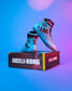 A pair of Godzilla-Kong themed high-top wrestling shoes in light blue, black, and red, displayed on top of their branded black and red shoebox against a vibrant blue and purple gradient background.
