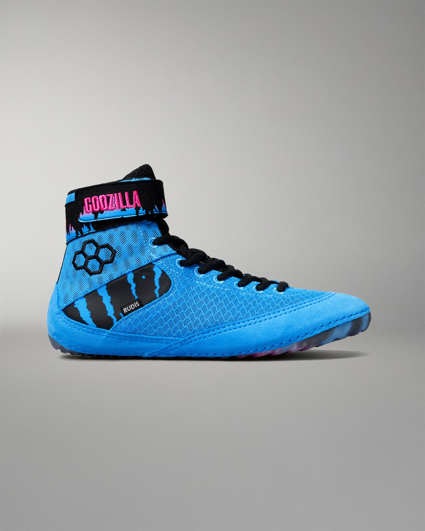 A high-top wrestling shoe in bright blue with black details, featuring a black ankle strap with pink 'GODZILLA' text and a black claw-stripe graphic on the side.