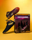 A pair of black and yellow Godzilla-themed wrestling shoes displayed next to their retail packaging box on a yellow studio background. The box features Godzilla and King Kong artwork with the text 'Godzilla Kong' and 'MonsterVerse'.