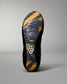 The outsole of a black wreslting shoe with a yellow and gray abstract pattern and a small white geometric logo near the center, shown against a neutral gray background.