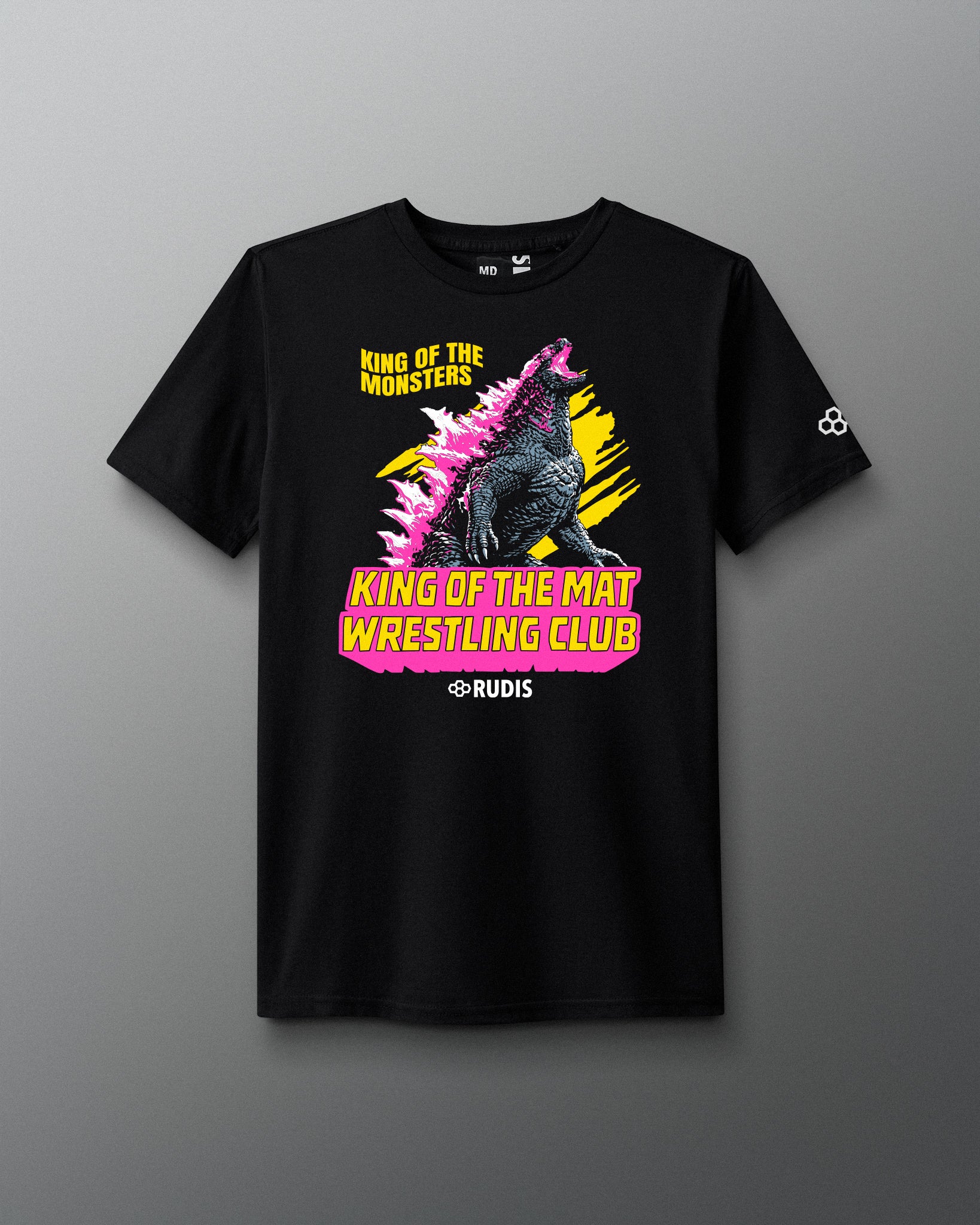 A black short-sleeve graphic t-shirt featuring a Godzilla design with pink spikes, yellow text reading 'King of the Mat Wrestling Club', and the Rudis brand name printed below the graphic, displayed against a neutral gray background.