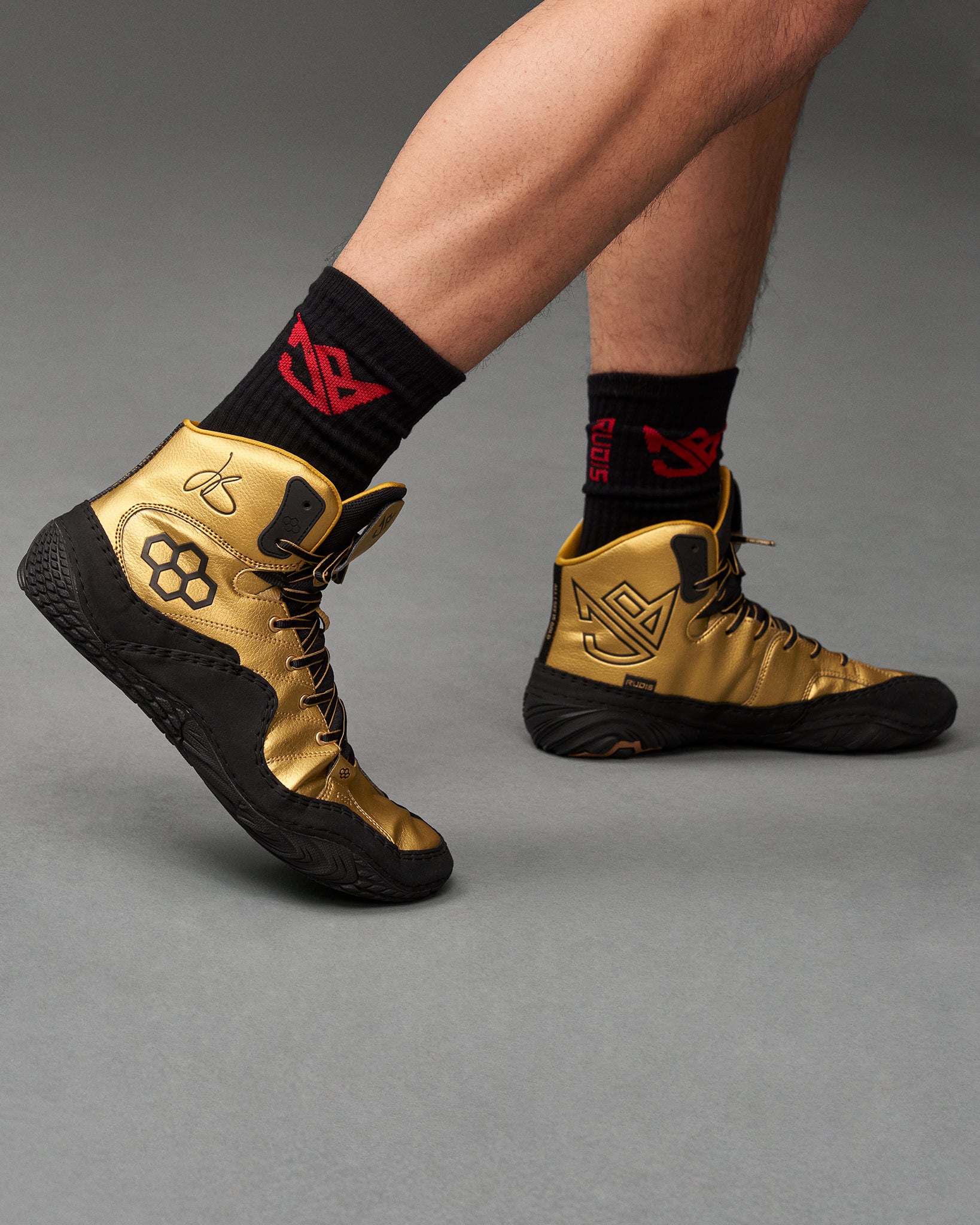 This visual features a dynamic view of a basketball player wearing stylish gold high-top sneakers with black soles complemented by black socks adorned with a red logo