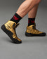 This visual features a dynamic view of a basketball player wearing stylish gold high-top sneakers with black soles complemented by black socks adorned with a red logo