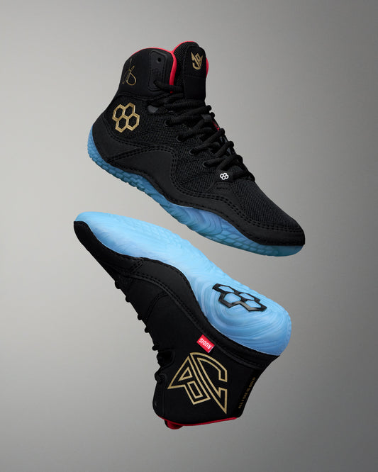 Black wrestling shoe with blue soles on a gray background