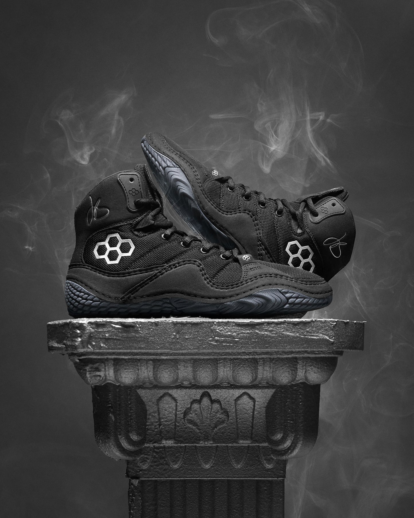 Black Jordan Burroughs wrestling shoes with a brand logo on a dark background
