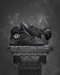 Black Jordan Burroughs wrestling shoes with a brand logo on a dark background