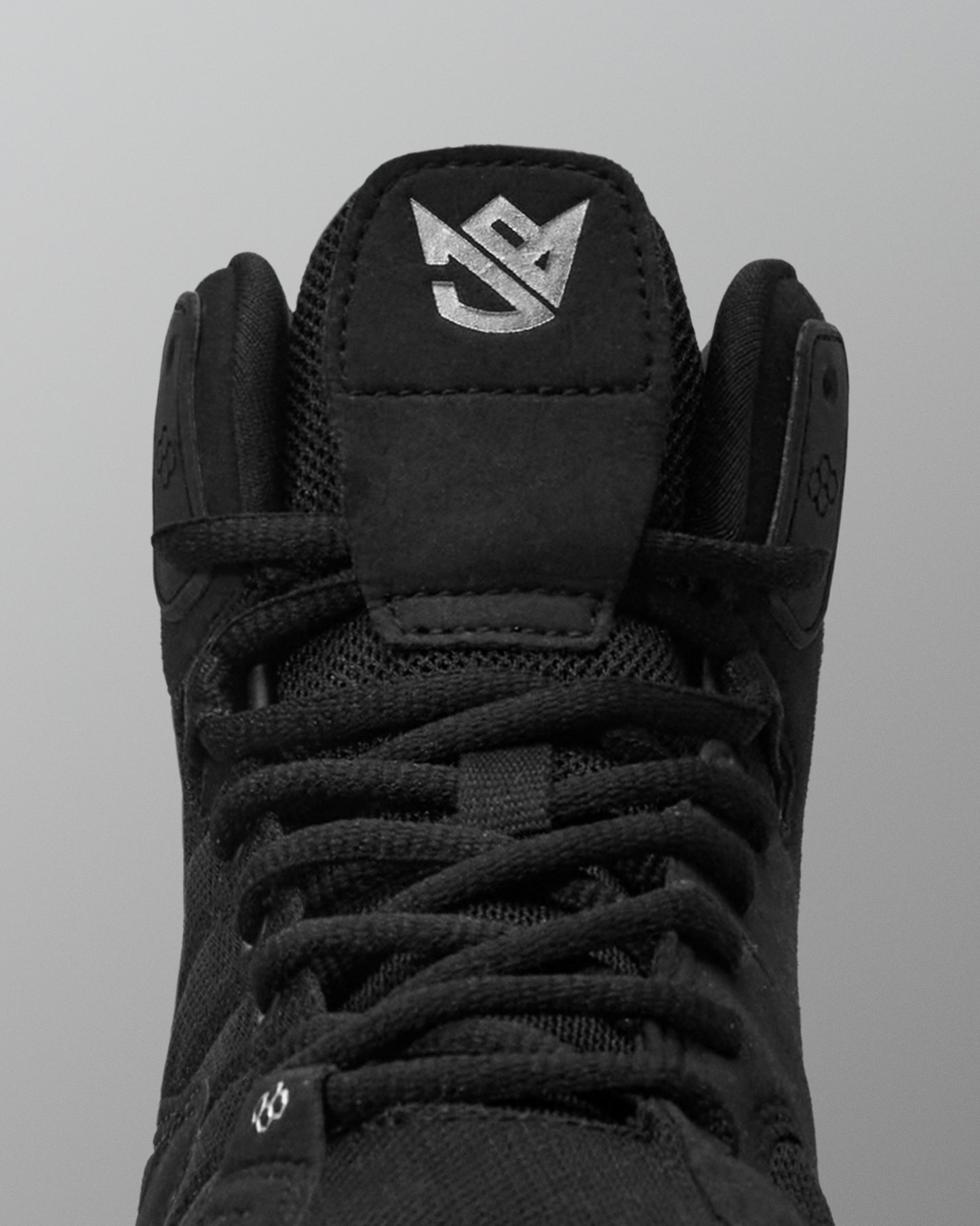 Black Jordan Burroughs wrestling shoes with a brand logo on a gray background