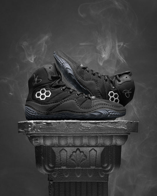 Black Jordan Burroughs wrestling shoes with a brand logo on a dark background