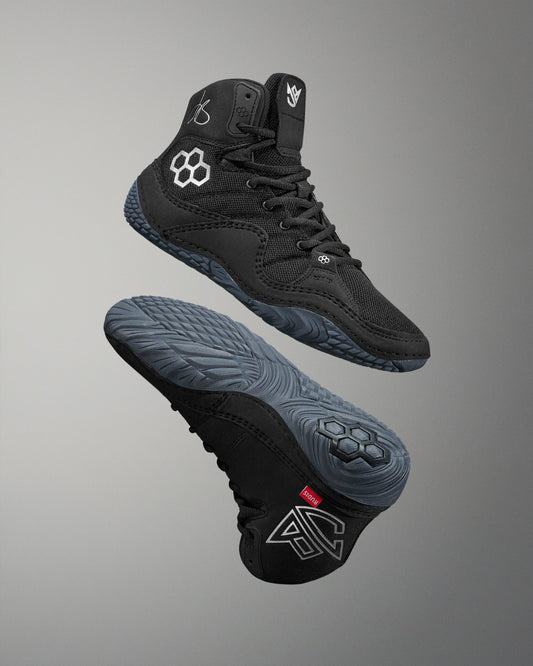 Black Jordan Burroughs wrestling shoes with brand logo on a gray background