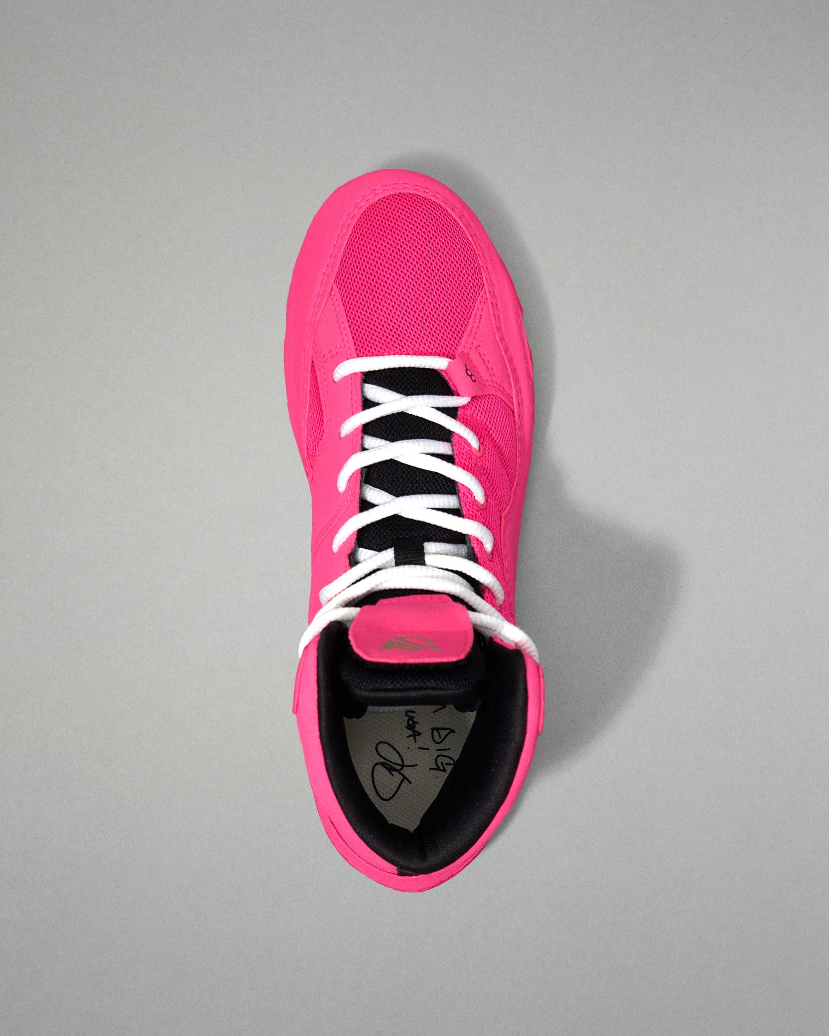Pink wrestling shoe with white laces on a gray background