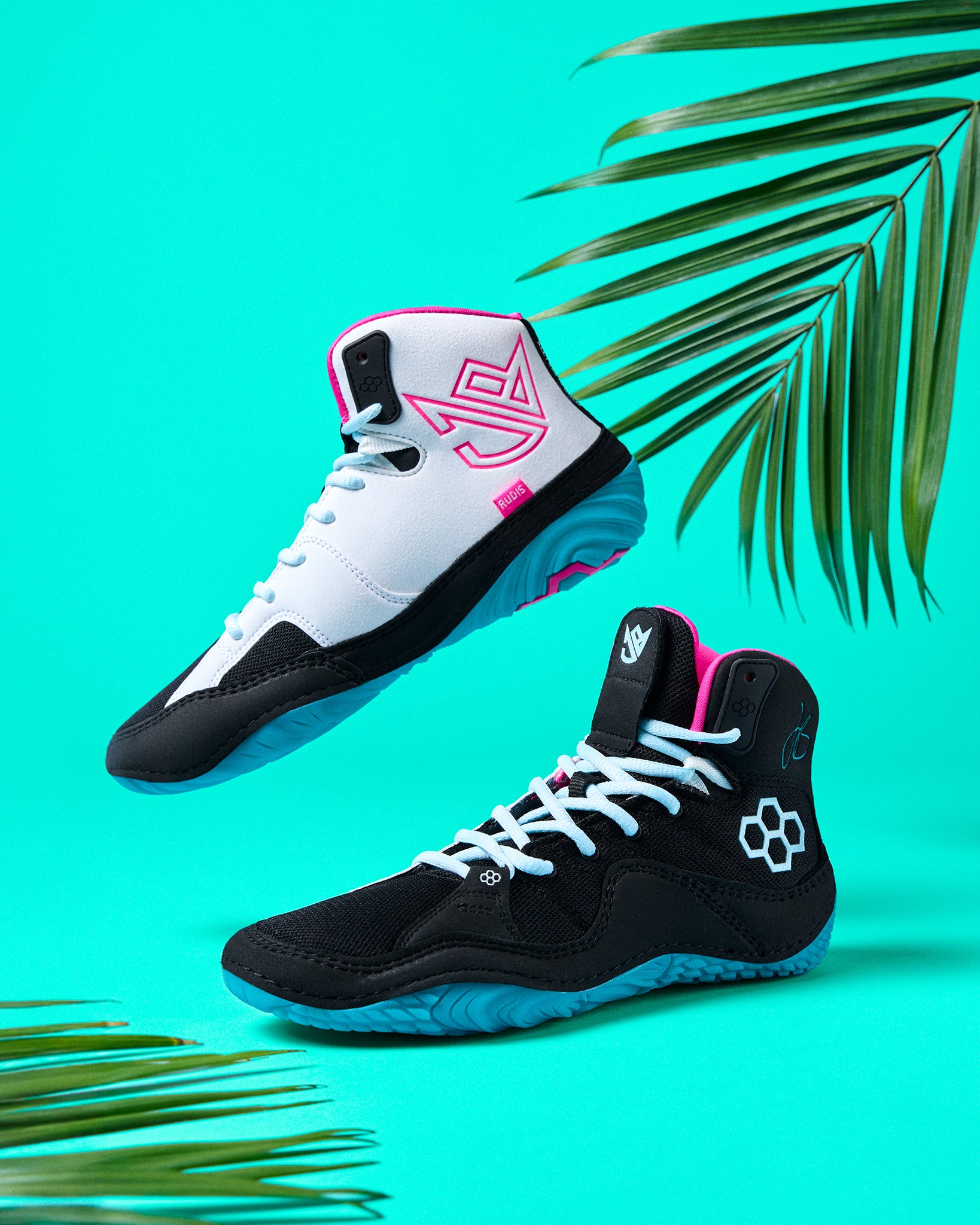 Black and white wrestling shoe with pink accents on a turquoise background with palm leaves.