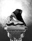 Black and white Jordan Burroughs Wrestling shoes on a decorative pedestal with a smoky background