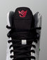Close-up of a wrestling shoe with a black tongue and red logo on a gray background