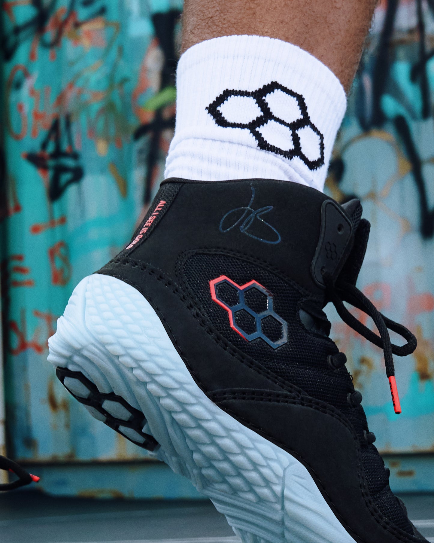 Close-up of the RUDIS JB1 Dark Shark adult wrestling shoe featuring a black upper, icy translucent outsole, red-accented RUDIS logo, and JB signature, paired with white RUDIS crew socks.
