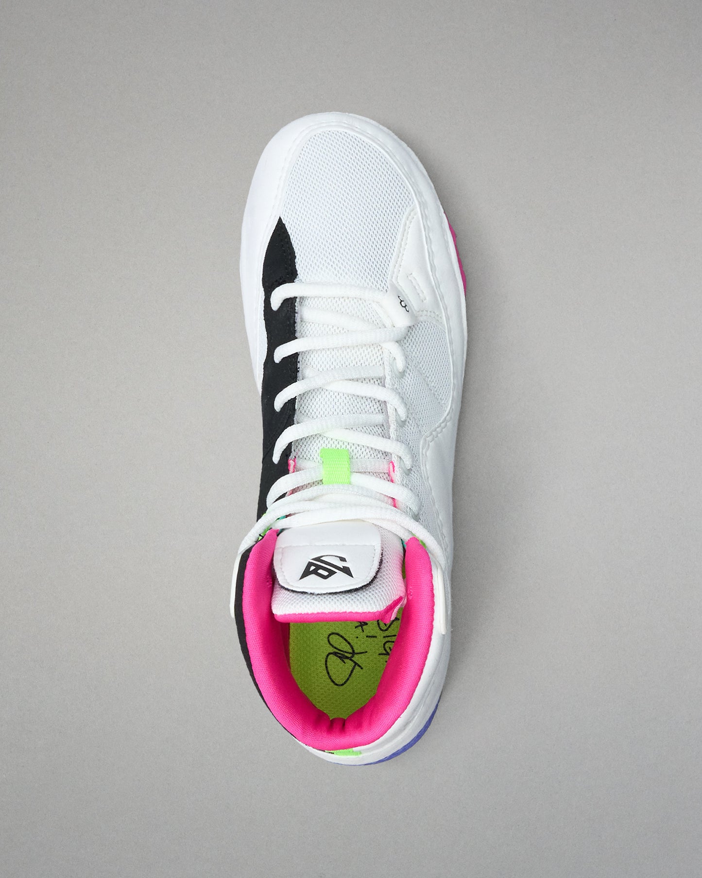 White wrestling shoe with black, pink, and green accents on a gray background