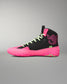 A high-top wrestling shoe in black and neon pink, featuring lime green laces and a small green 'RUDIS' logo on the side, set against a neutral gray background.