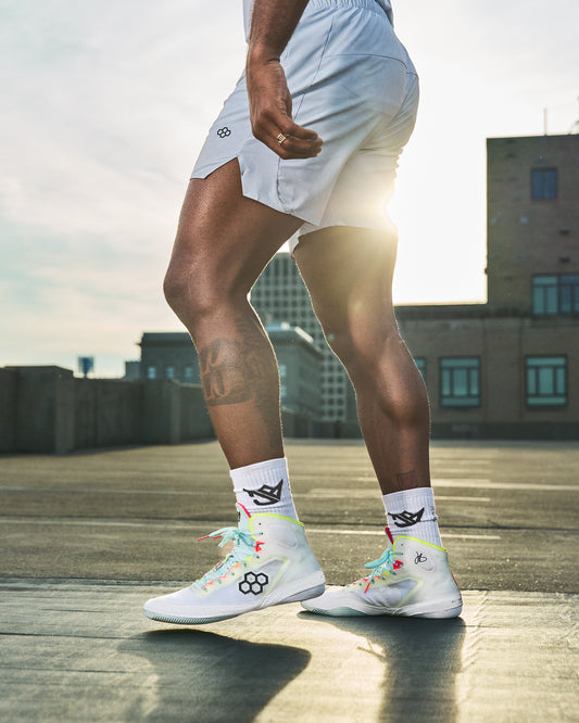 Person wearing white athletic shoes with colorful accents on a rooftop.