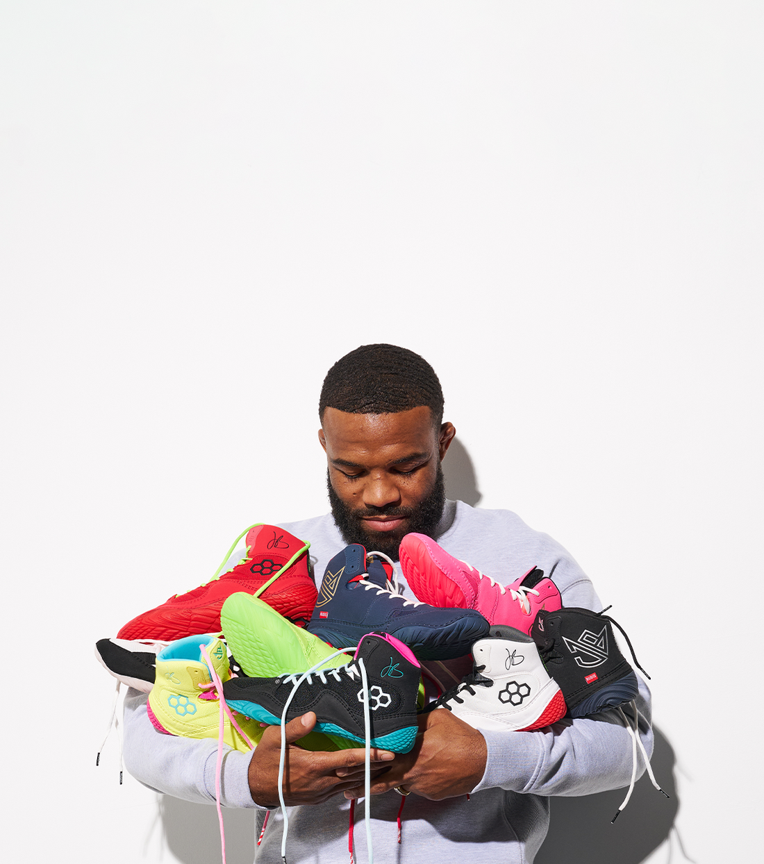 Jordan Burroughs holding JB1 wrestling shoes by RUDIS, multiple colorways performance wrestling shoes co-designed by Olympic champion