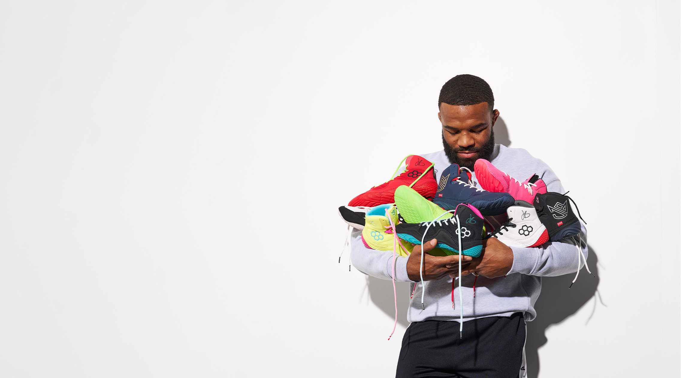 Jordan Burroughs holding JB1 wrestling shoes by RUDIS, multiple colorways performance wrestling shoes co-designed by Olympic champion