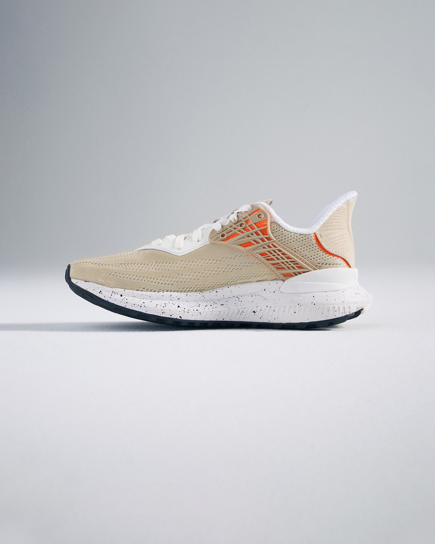 Side view of a modern beige athletic shoe featuring a breathable mesh upper vibrant orange accents and a textured sole designed for traction and comfort