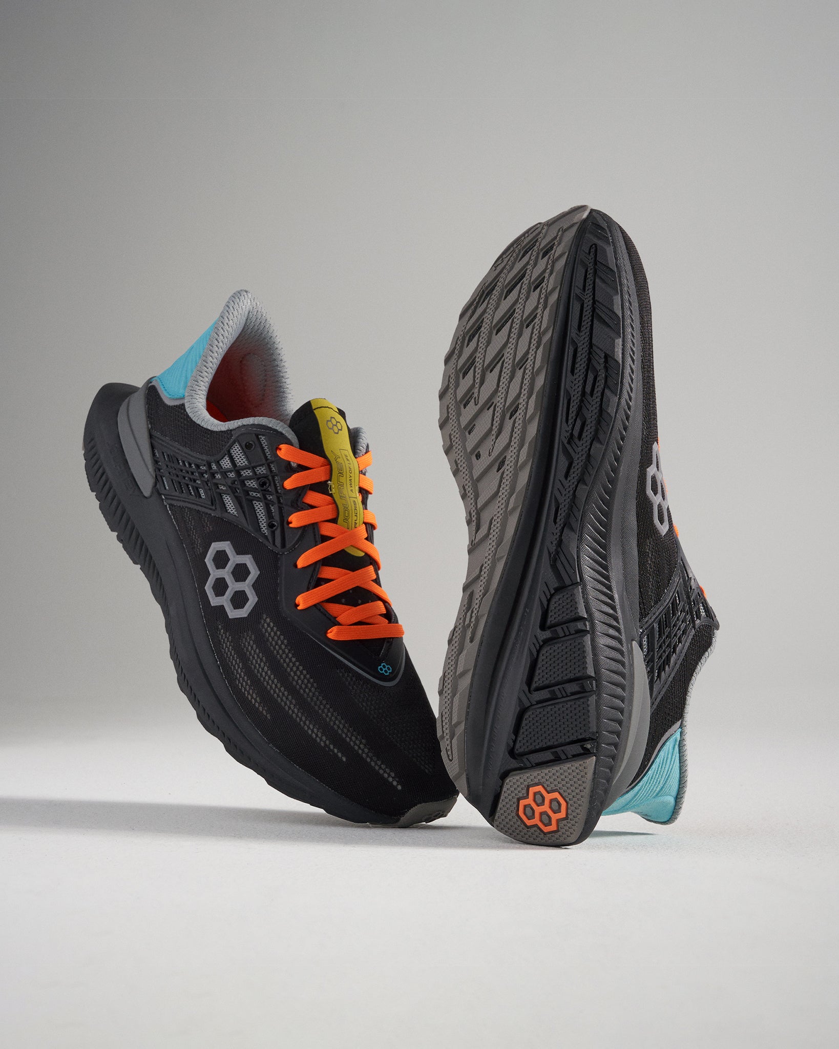A pair of innovative black running shoes featuring vibrant orange laces a textured sole and a breathable design for enhanced performance