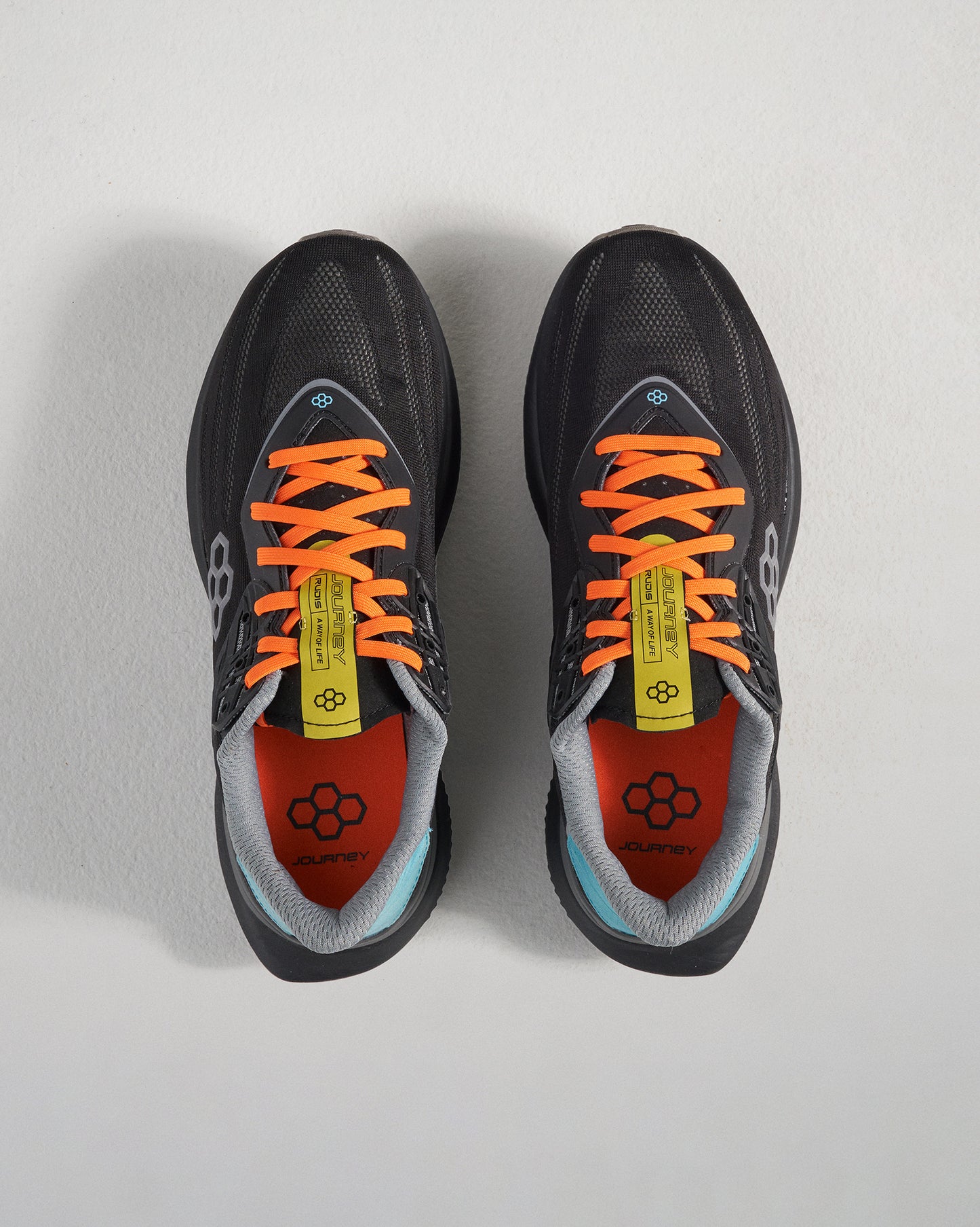 A pair of modern black running shoes with vibrant orange laces and a sleek design featuring a branded interior and multi-color accents