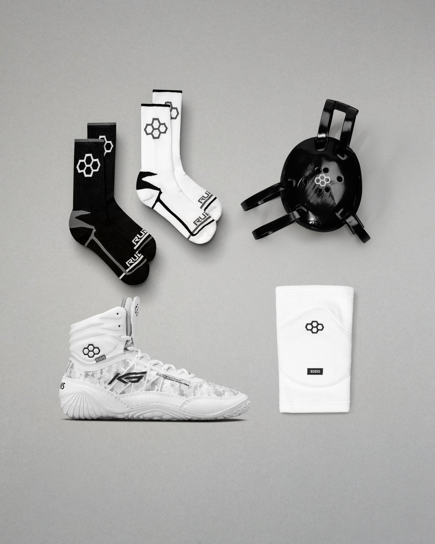White wrestling shoes, black and white socks, and a black headgear on a gray background