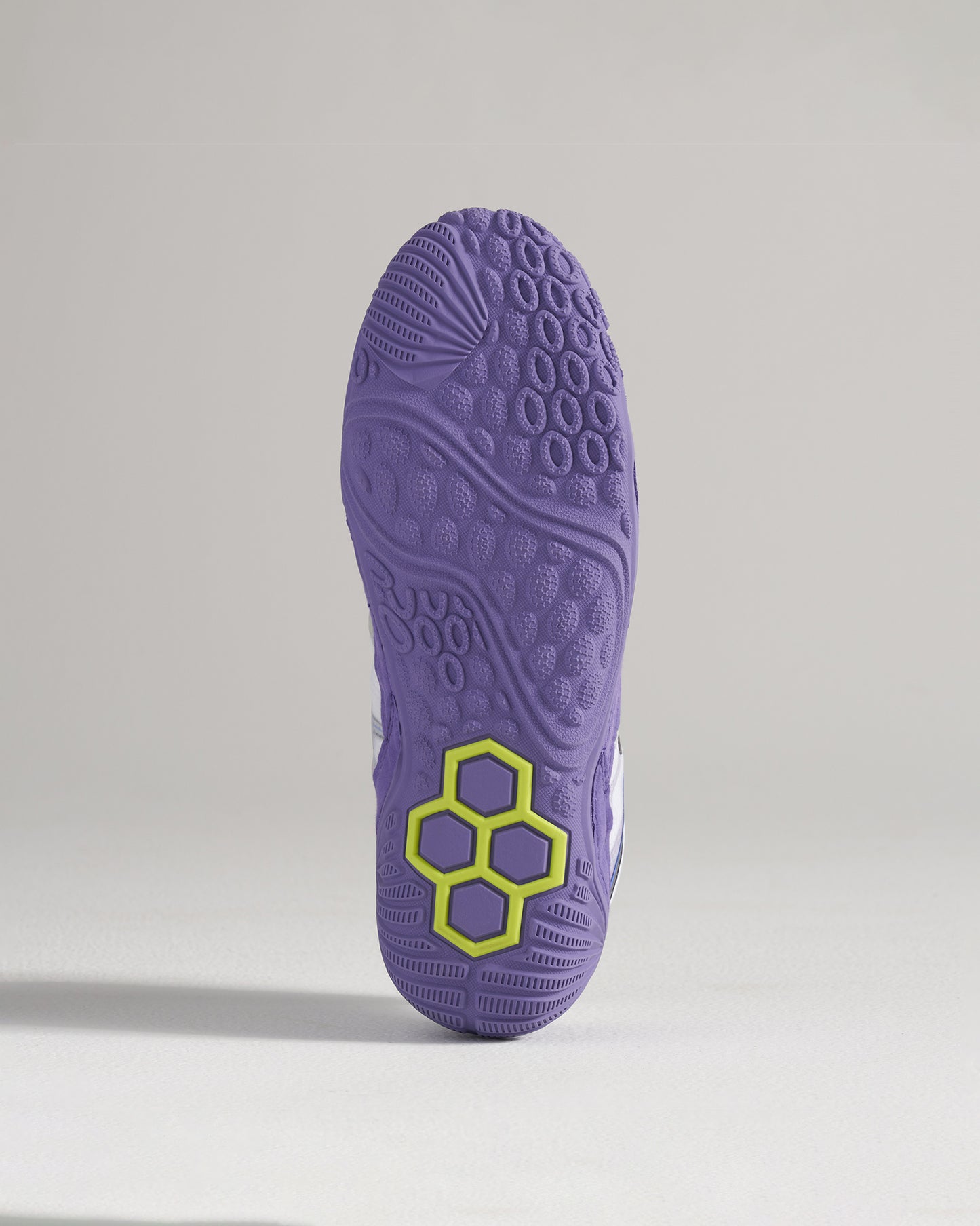 A detailed view of a purple athletic shoes outsole showcasing a unique tread pattern and a distinct hexagonal logo in green
