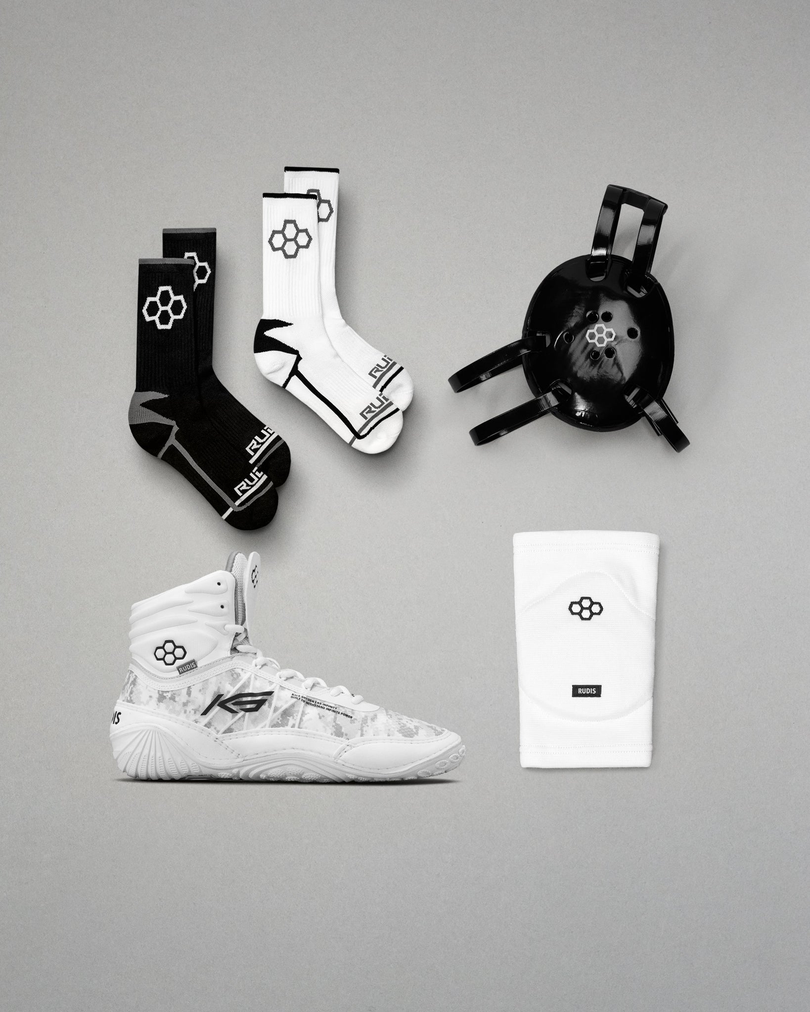 White wrestling shoes, black and white socks, and a black headgear on a gray background