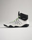 A modern white and black high-top athletic shoe with green accents featuring a unique design and textured sole for enhanced performance