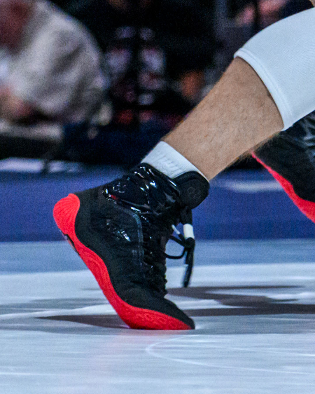 Black and red wrestling shoes on a wrestling mat with blurred background
