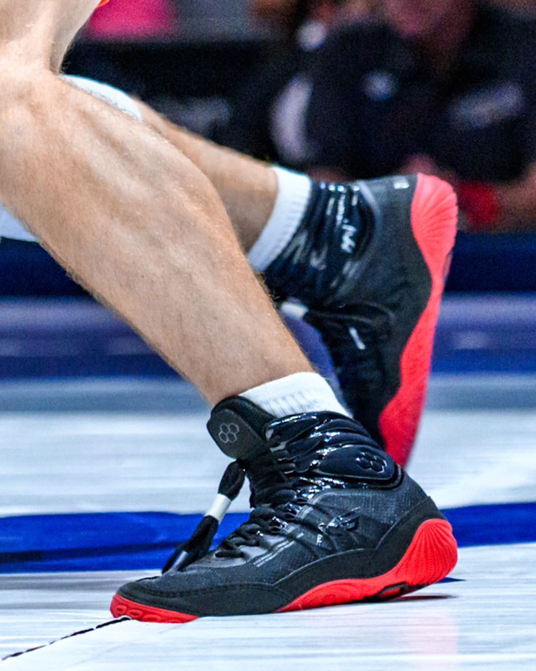 Close-up of black and red wrestling shoes on a wrestling mat