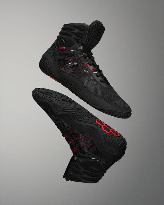 High-performance black wrestling shoes, designed for grip and support, showcase a breathable upper and textured sole against a soft gray background.