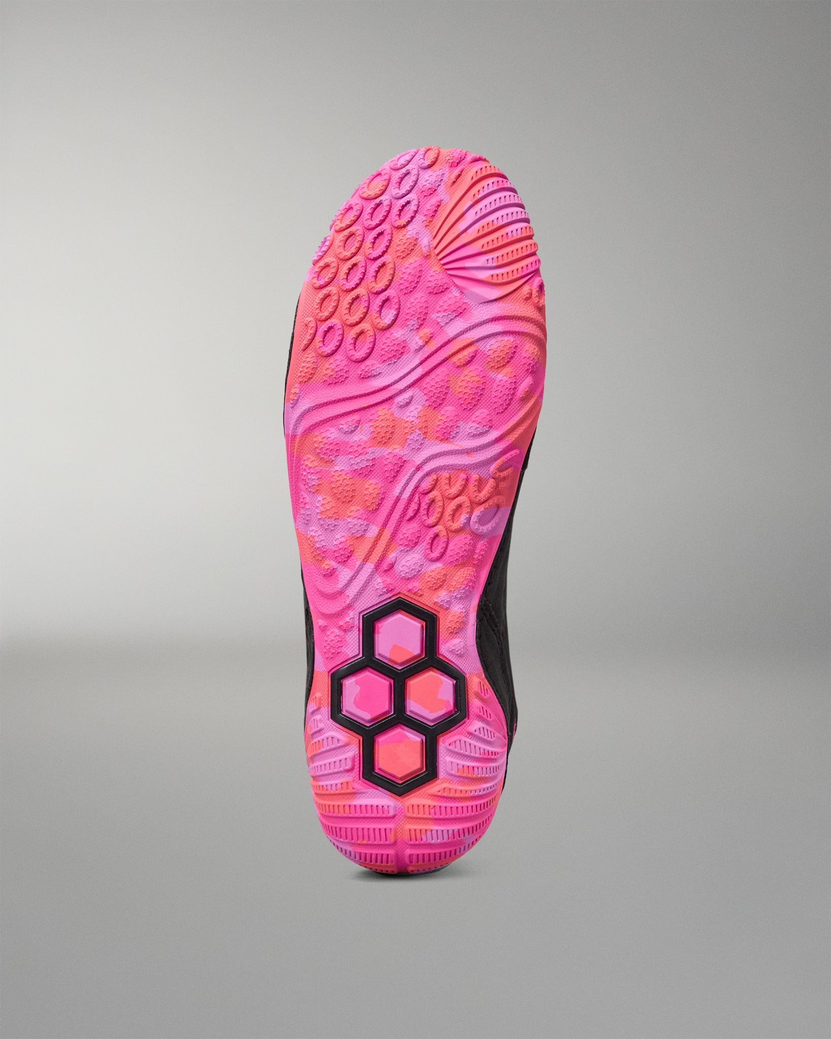 The outsole of a wrestling shoe shown from the bottom, featuring a vibrant pink and orange wavy tread pattern with a black and pink hexagonal logo near the heel, set against a neutral gray background.